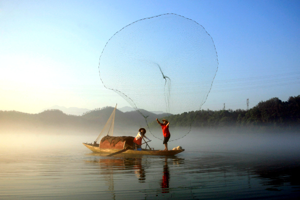 Reuters/China Daily - A fisherman casts his net to catch fish on the Xin'an River in Jiande, Zhejiang Province, China, in July. A group of highly skilled volunteer professional divers scours the world's oceans to remove old fishing nets that can harm sea life.
